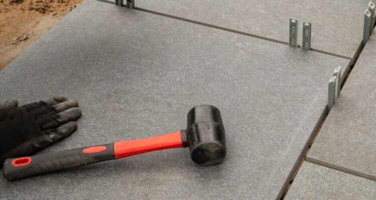 Grey patio slabs being installed with rubber mallet | Building Material reviews