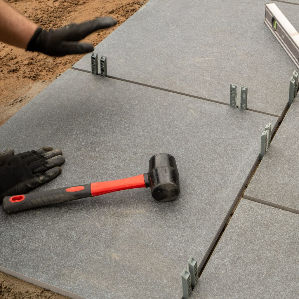 Grey patio slabs being installed with rubber mallet | Building Material reviews